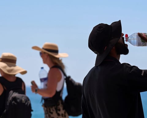 Tourist drinks water at a beach during the record-breaking June 2026 European heatwave