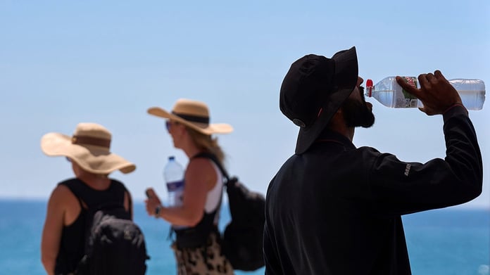 Tourist drinks water at a beach during the record-breaking June 2026 European heatwave
