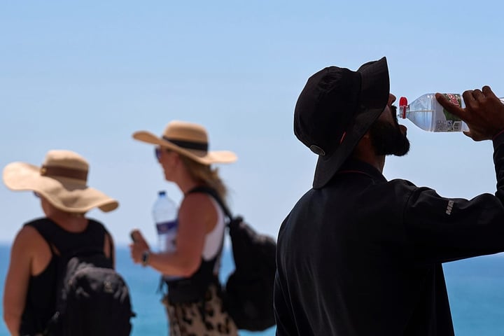 Tourist drinks water at a beach during the record-breaking June 2026 European heatwave