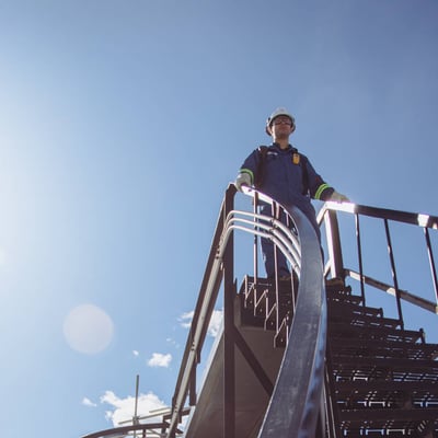 An ExxonMobil field worker stands on industrial stairs at a Permian Basin facility