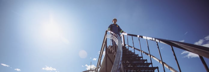 An ExxonMobil field worker stands on industrial stairs at a Permian Basin facility