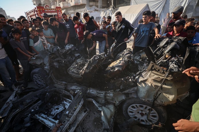 Palestinians gather around destroyed vehicles after Israeli strikes on Gaza