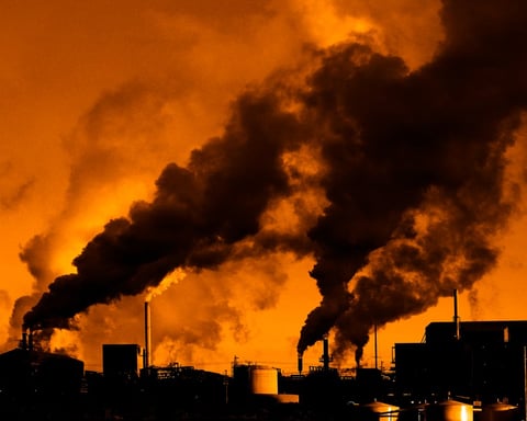 Industrial smokestacks representing carbon emissions from AI data center expansion by Google and Amazon