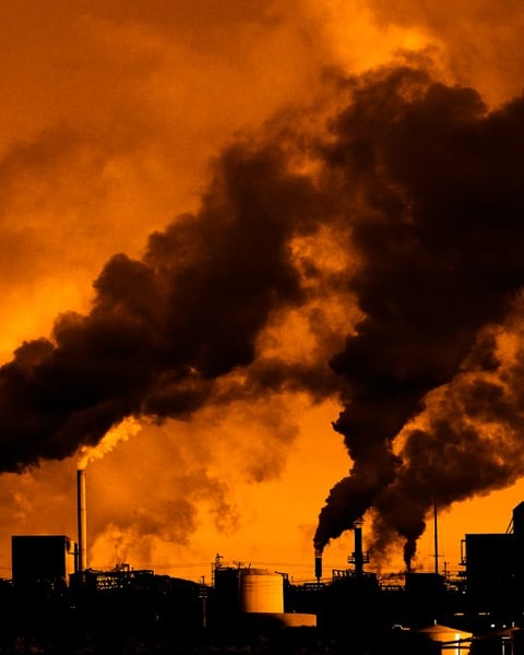 Industrial smokestacks representing carbon emissions from AI data center expansion by Google and Amazon