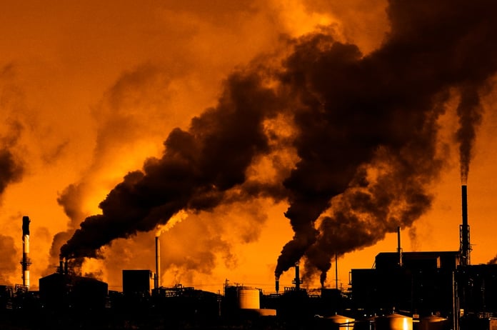 Industrial smokestacks representing carbon emissions from AI data center expansion by Google and Amazon