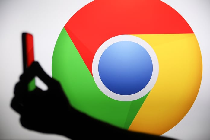 Person holding a phone displaying the Google Chrome logo, representing AI-powered security patching in 2026