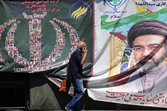 A man walks past a banner of Iran supreme leader Ayatollah Mojtaba Khamenei on a Tehran street during the Iran-Israel war 2026