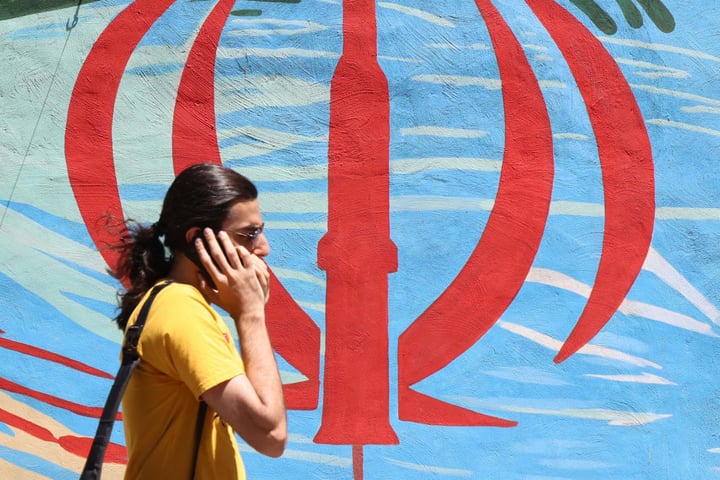 An Iranian man walks past an anti-US and anti-Israel mural in Tehran, May 2026