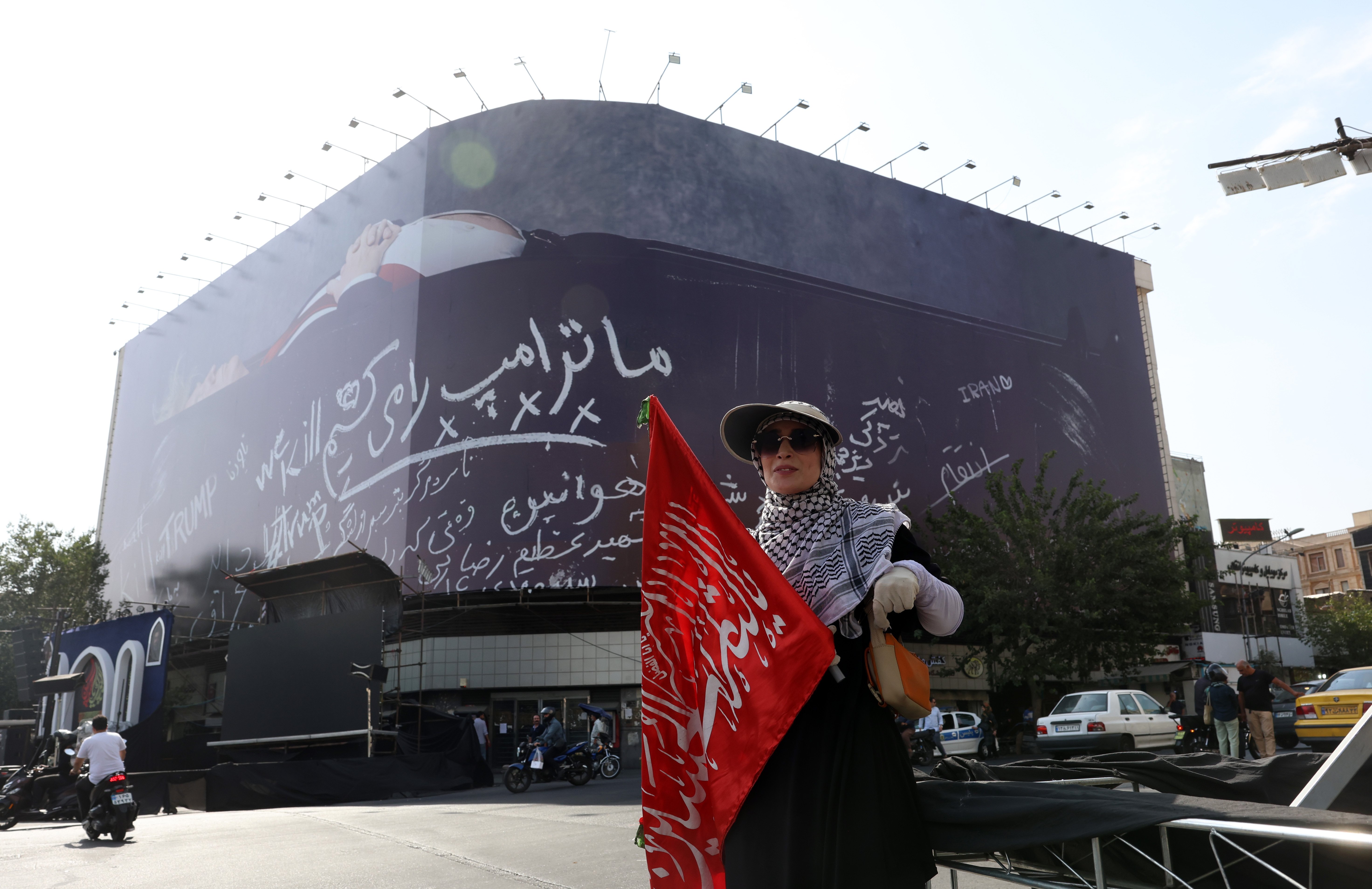 Iranian woman next to anti-US billboard depicting Donald Trump in coffin at Enghelab Square Tehran Iran 2026