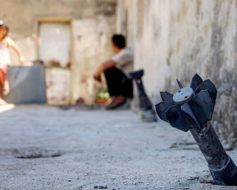 A man and child near unexploded artillery shell from Israeli bombardment in Syria Daraa province near Golan Heights June 2026