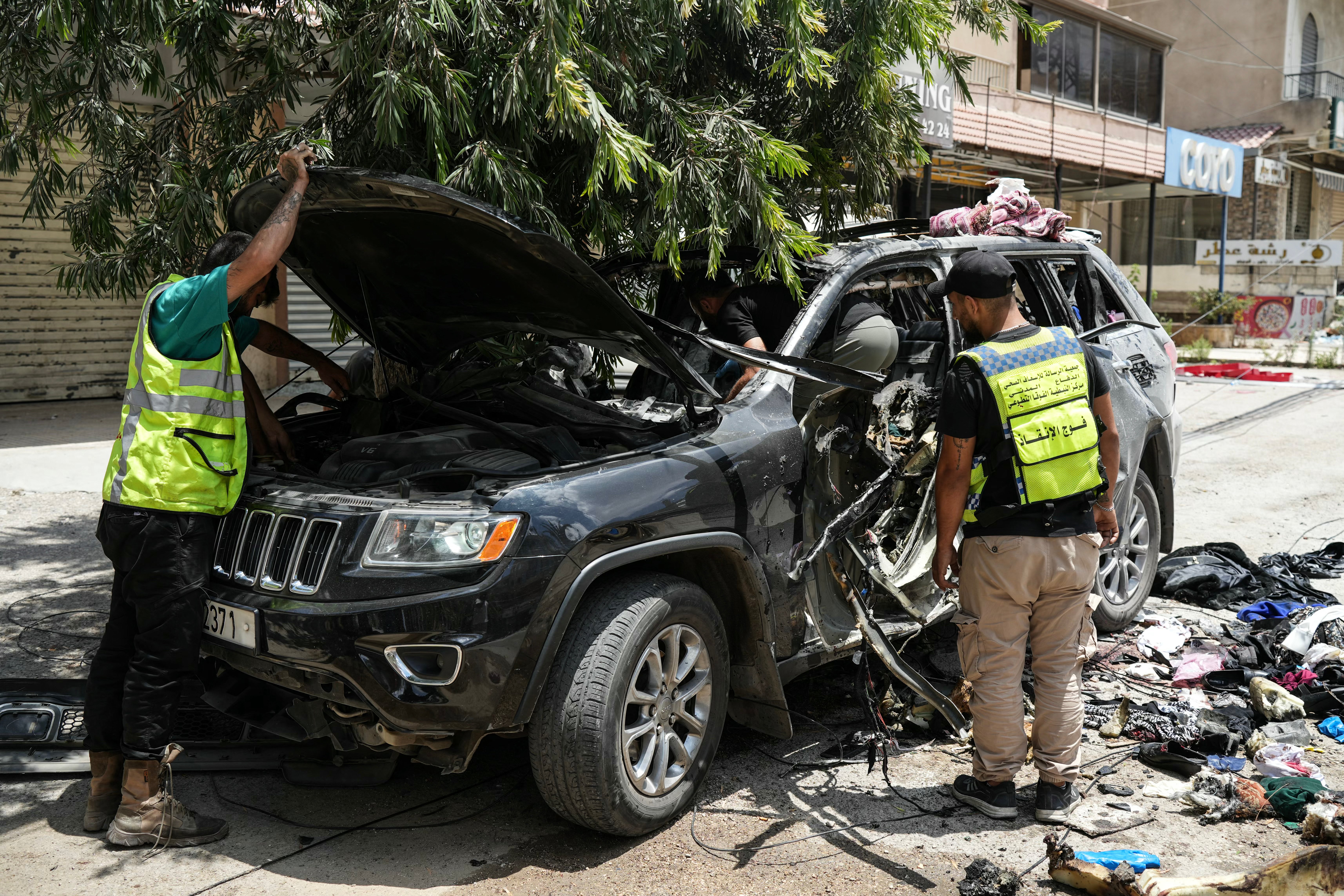 First responders inspect a vehicle destroyed by an Israeli strike in Nabatieh, southern Lebanon