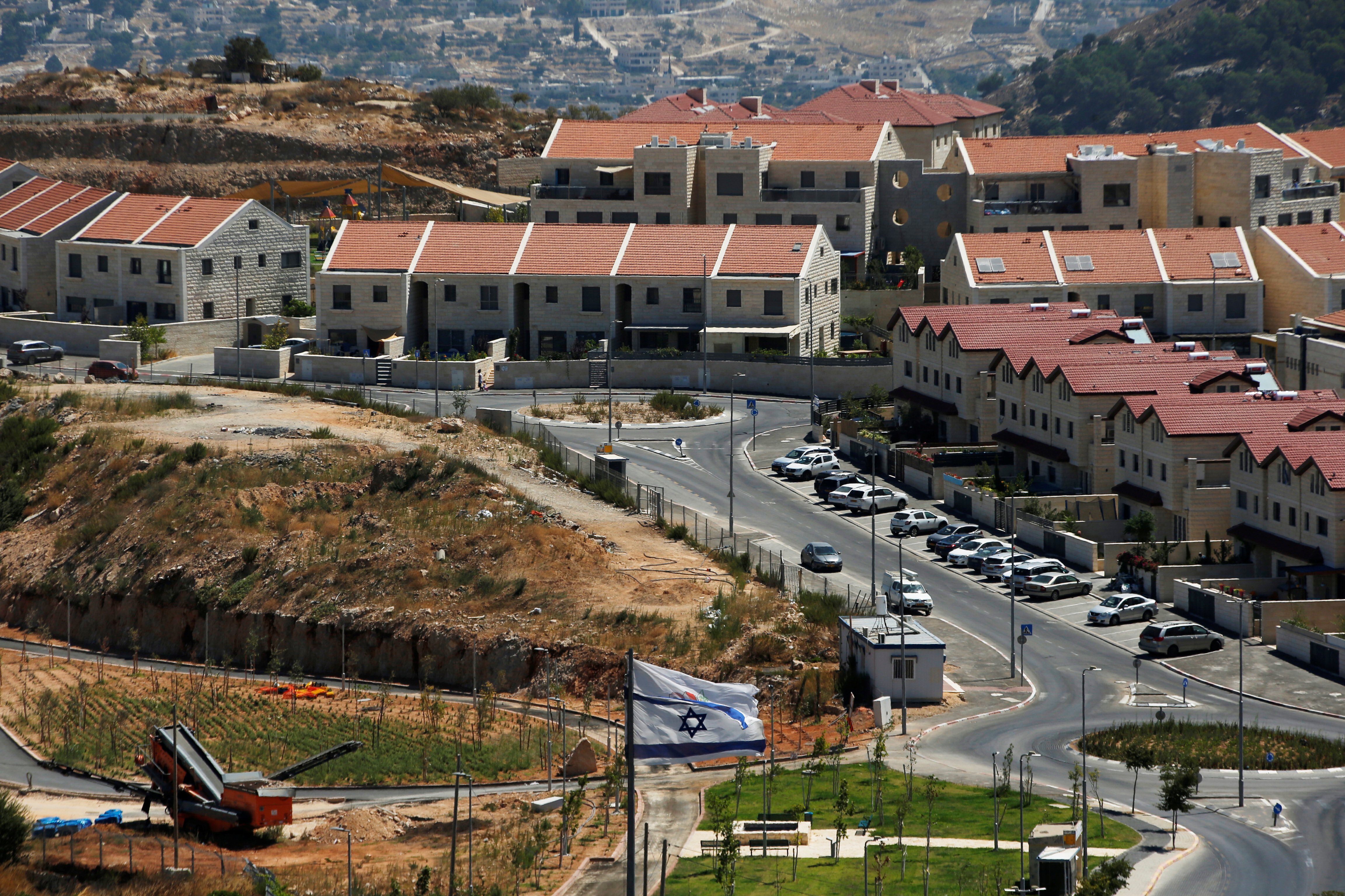 Israeli settlement apartment buildings in Efrat, West Bank, with Israeli flag in foreground