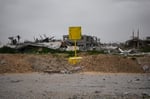 Palestinian family near yellow concrete blocks marking Israel's expanding buffer zone across the Gaza Strip