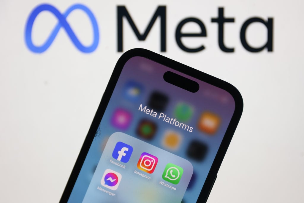 Meta logo on laptop screen with Facebook Instagram WhatsApp and Messenger icons on phone screen