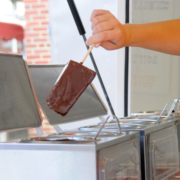 Vendor preparing frozen chocolate-dipped cheesecake on a stick at Ohio State Fair 2026