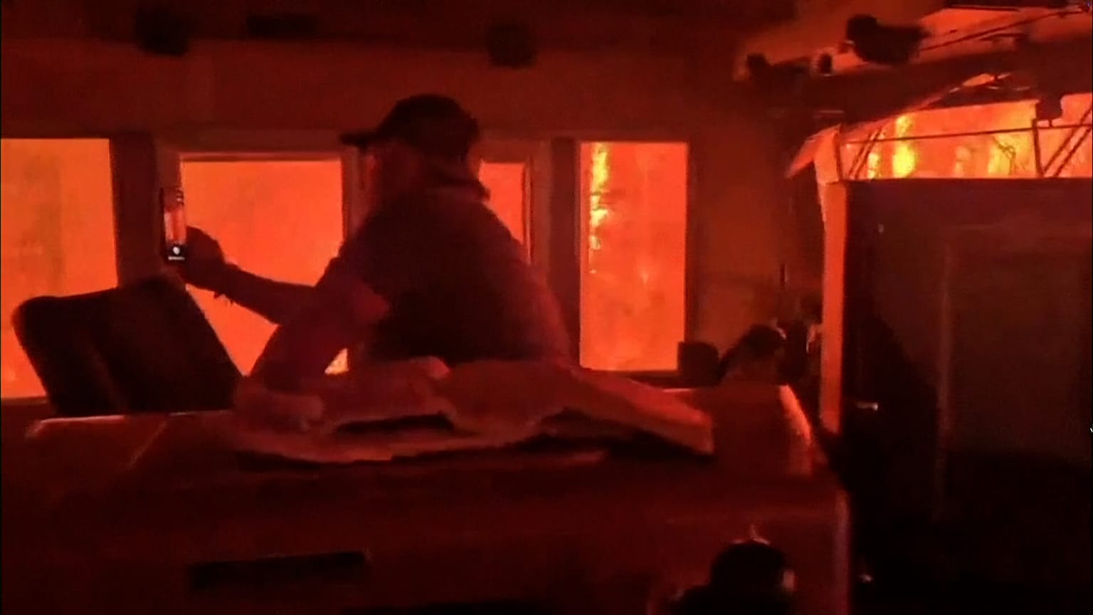 Freight train surrounded by wildfire flames near Armstrong Ontario with orange glow through windows