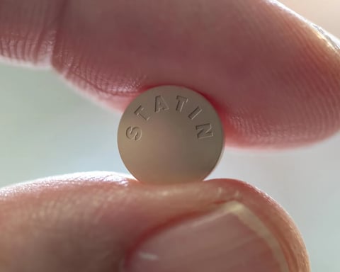 Person holding a statin pill close up for Oxford muscle risk study