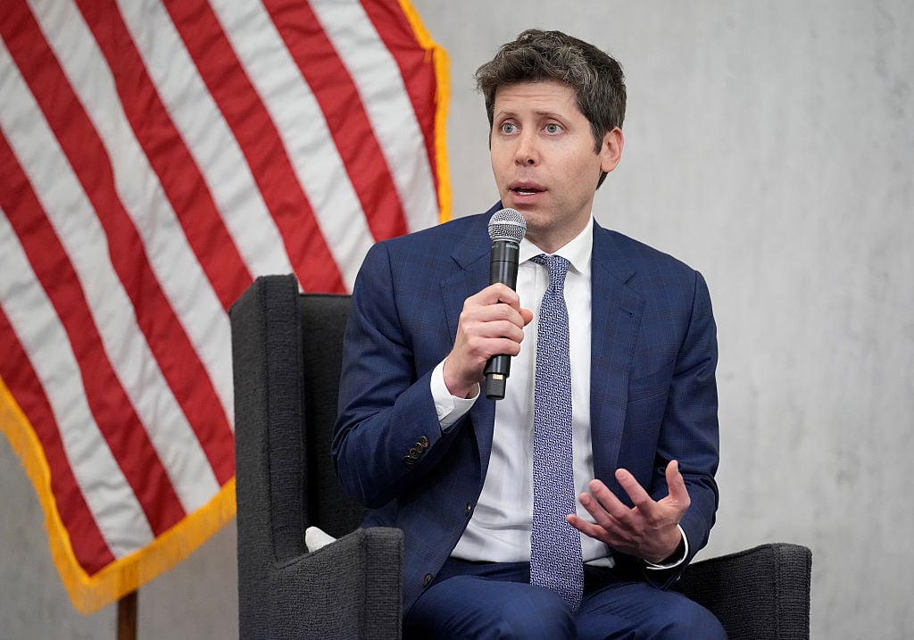 OpenAI CEO Sam Altman with American flag background at a Washington AI policy event