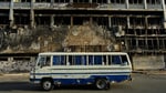 A bus drives past a destroyed hotel in Khartoum during Sudan's civil war