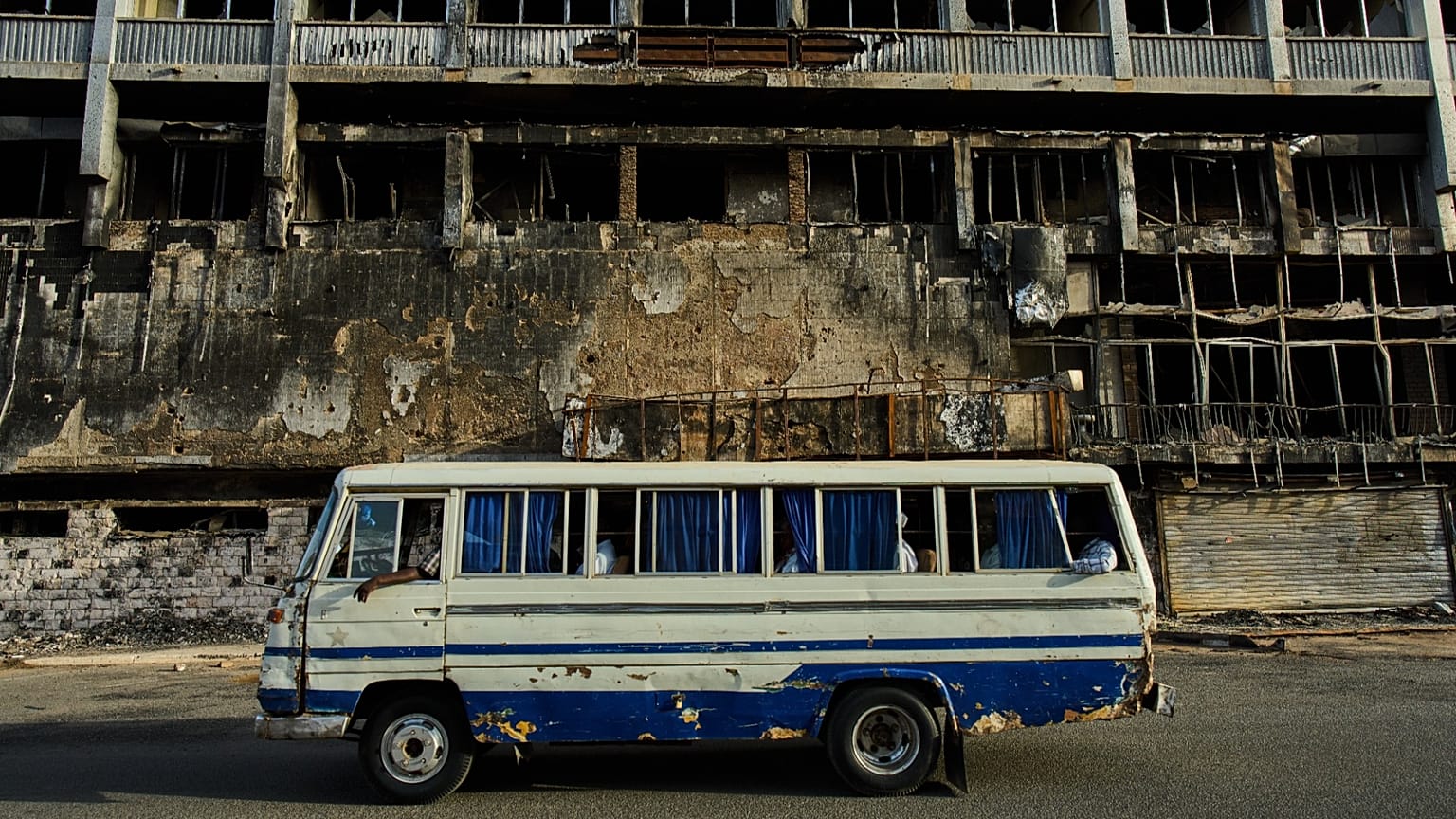 A bus drives past a destroyed hotel in Khartoum during Sudan's civil war