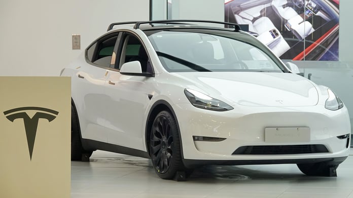 A white Tesla vehicle on a road, representing the NTSB and NHTSA investigation into Tesla Full Self-Driving crashes