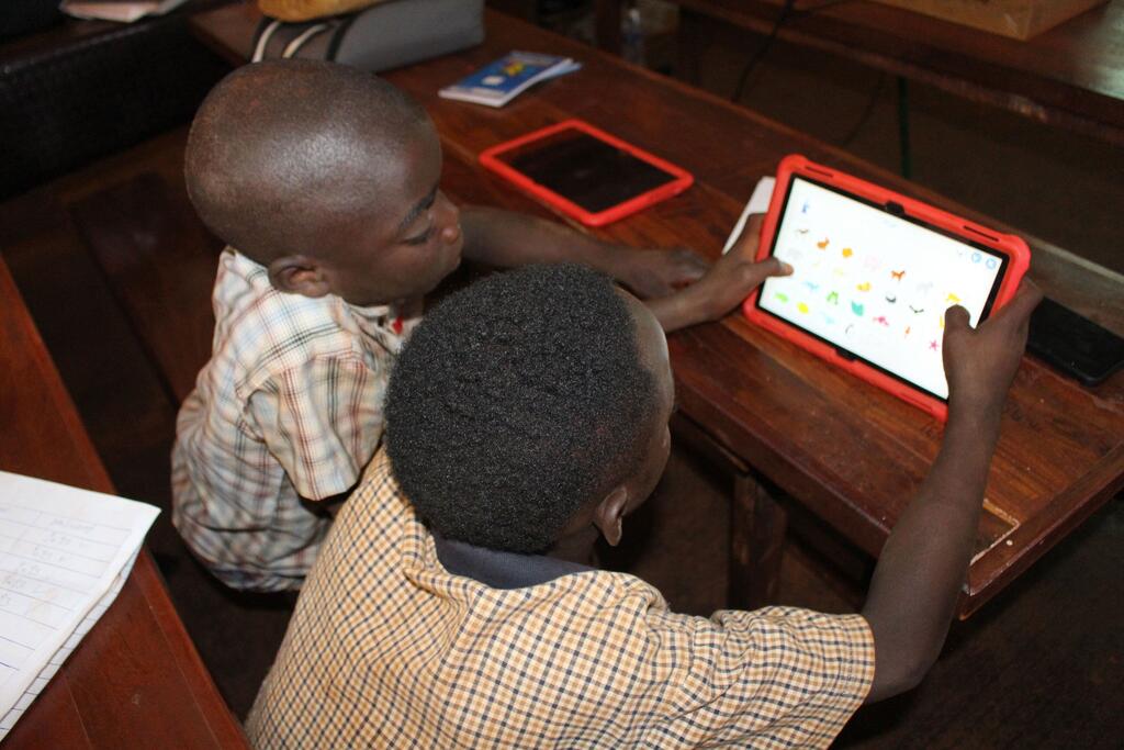 Students in Tanzania using digital tablets, illustrating the AI access divide at the center of UN AI governance negotiations in Geneva