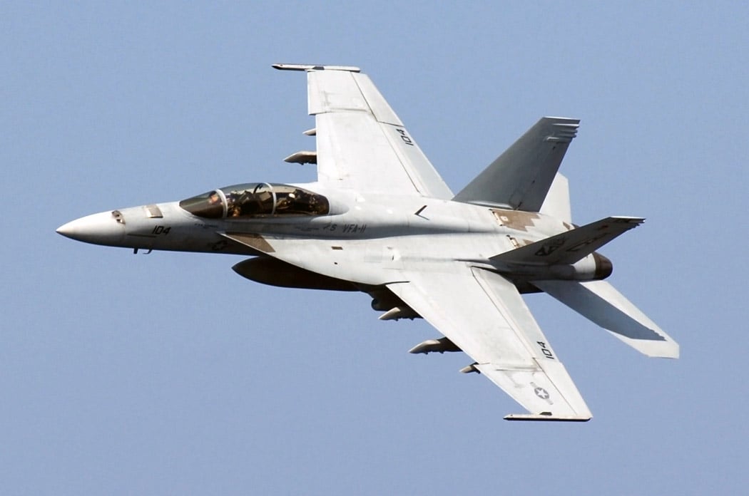 A US Navy F/A-18F Super Hornet from VFA-11 Red Rippers making a sharp turn above the USS Harry S. Truman aircraft carrier