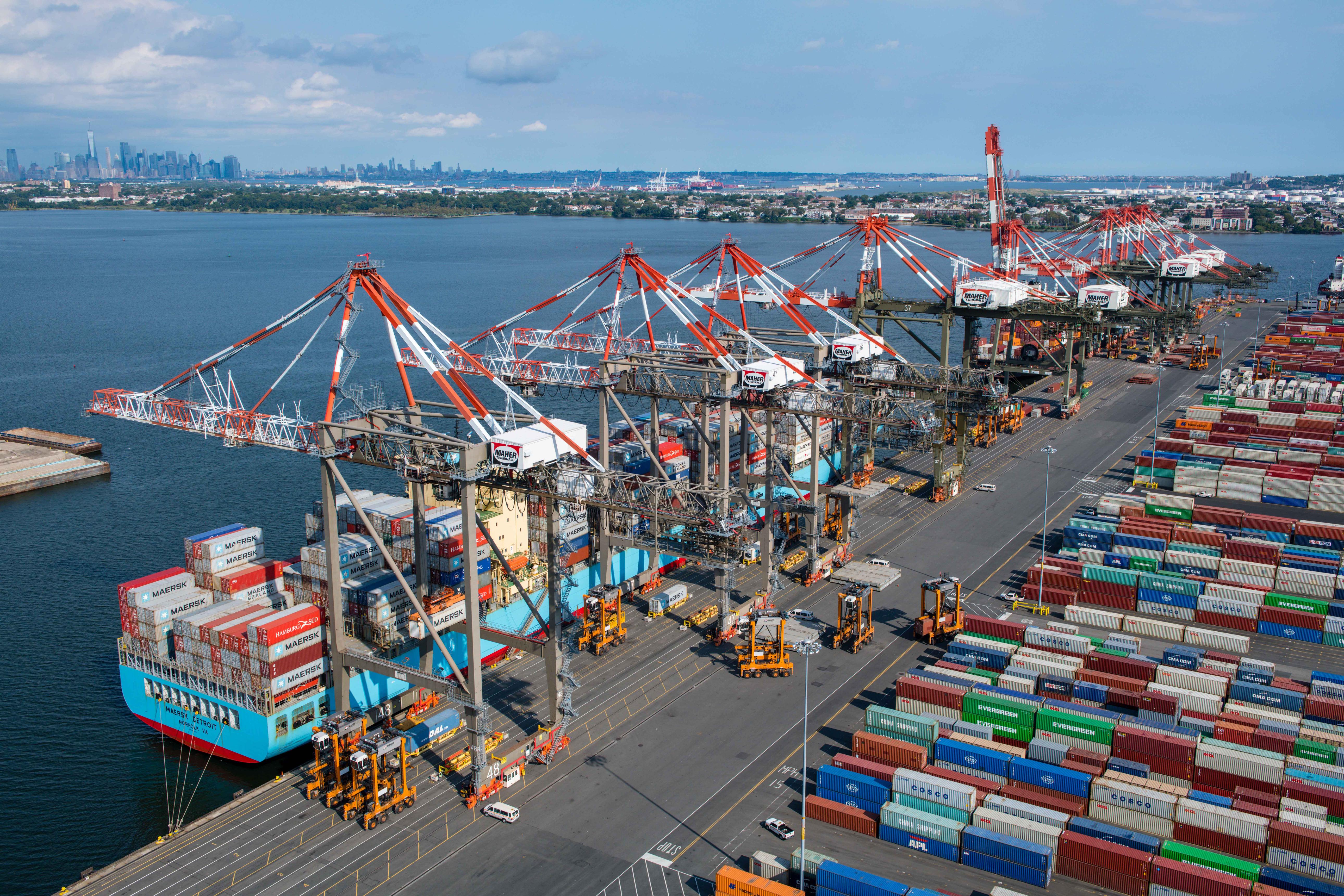 Container ships unload imported cargo at a US port as AI-driven capital goods imports push the May 2026 trade deficit higher.