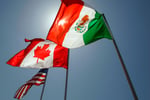 American, Canadian, and Mexican flags at a trade meeting illustrating USMCA relations