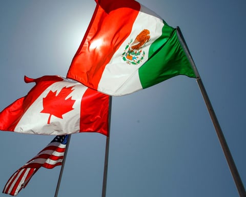 American, Canadian, and Mexican flags at a trade meeting illustrating USMCA relations