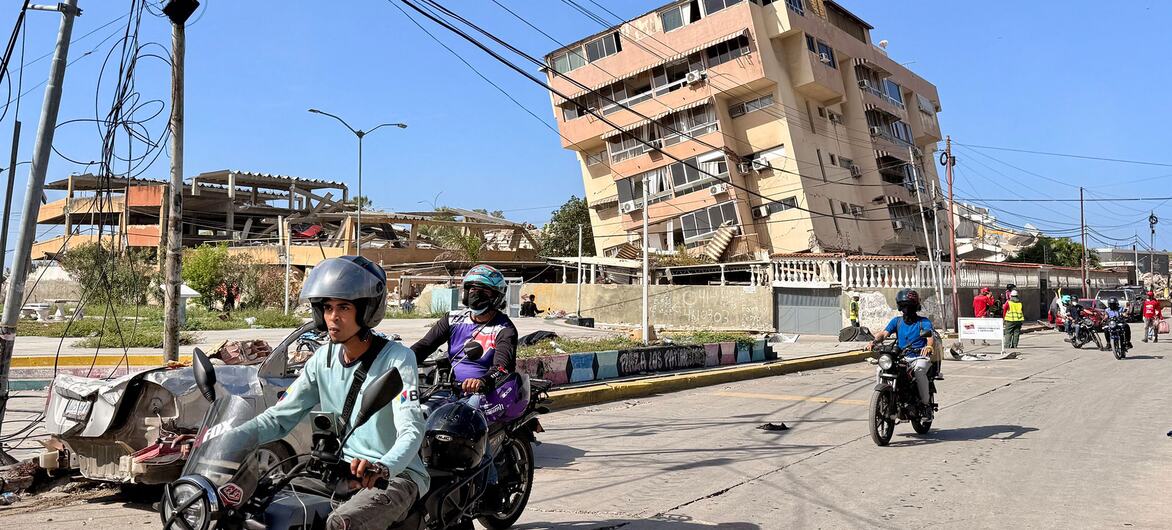 Motorcyclists pass through La Guaira Venezuela past damaged buildings earthquake 2026