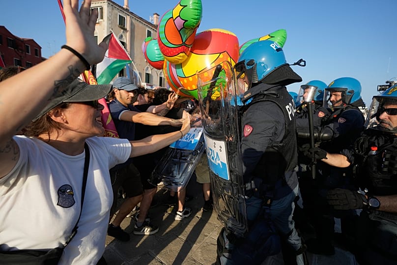 Demonstrators with protest signs face police at Venice's waterfront as Trump's ambassador Fertitta conducts his Coastal Diplomacy 250 tour in July 2026
