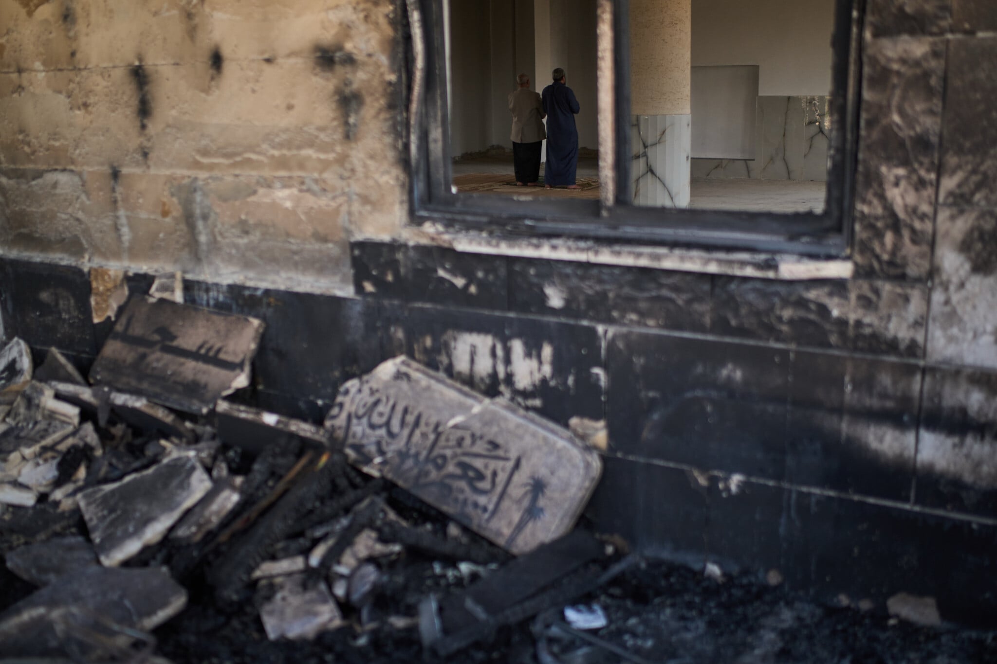 Palestinian worshippers praying inside a mosque damaged by arson attack in the West Bank