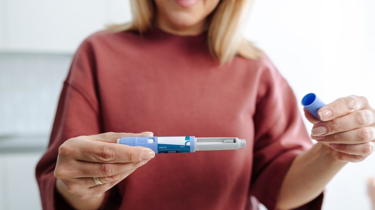 Woman holding GLP-1 injectable weight-loss medication
