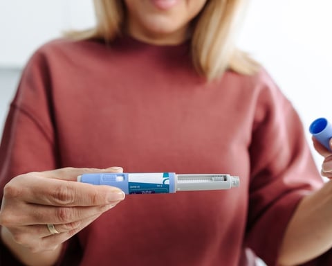 Woman holding GLP-1 injectable weight-loss medication