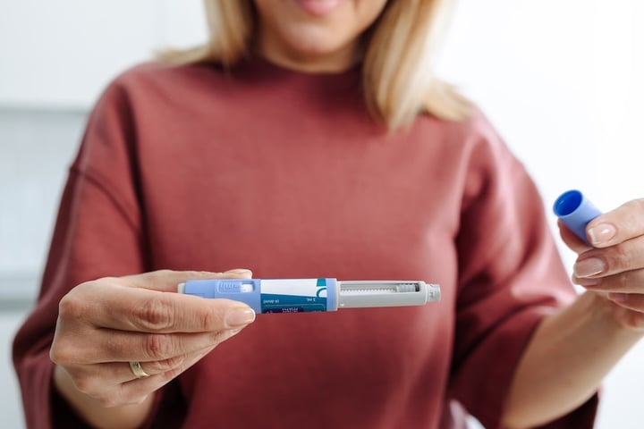 Woman holding GLP-1 injectable weight-loss medication