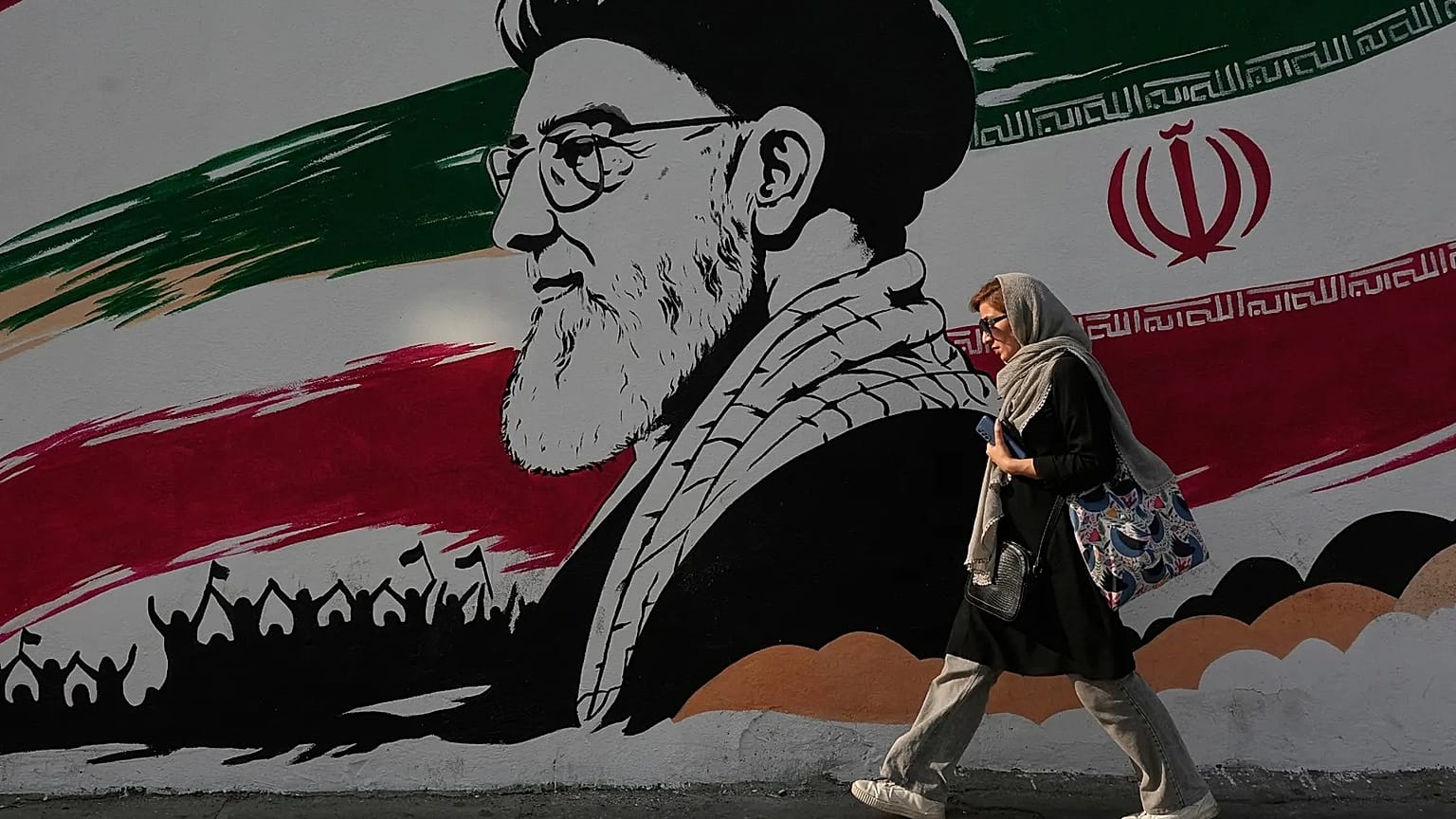 A woman walks past a large mural of the late Iranian Supreme Leader Ayatollah Ali Khamenei on Azadi (Freedom) Street in Tehran, July 2026