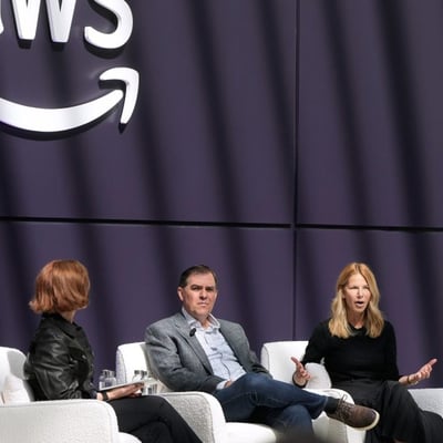 AMZN stock today: executives on stage beneath the Amazon Web Services logo, the division driving Amazon's AI infrastructure spending