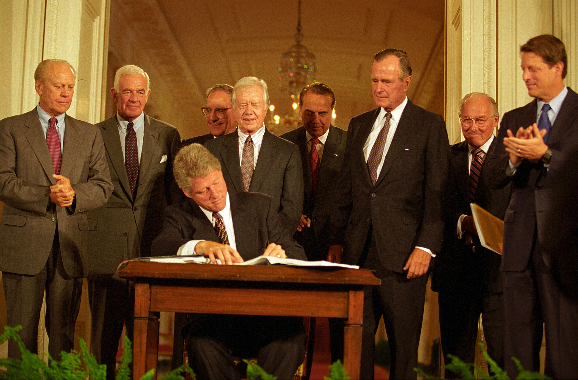 Bill Clinton seated at a desk signing the North American Free Trade Agreement implementation act in December 1993