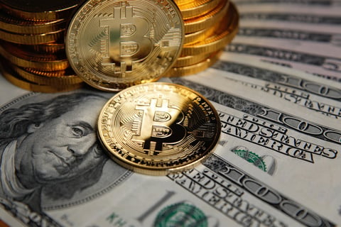 Bitcoin coins stacked on US dollar banknotes representing $130 million stolen from Coldcard hardware wallet users through a seed phrase vulnerability