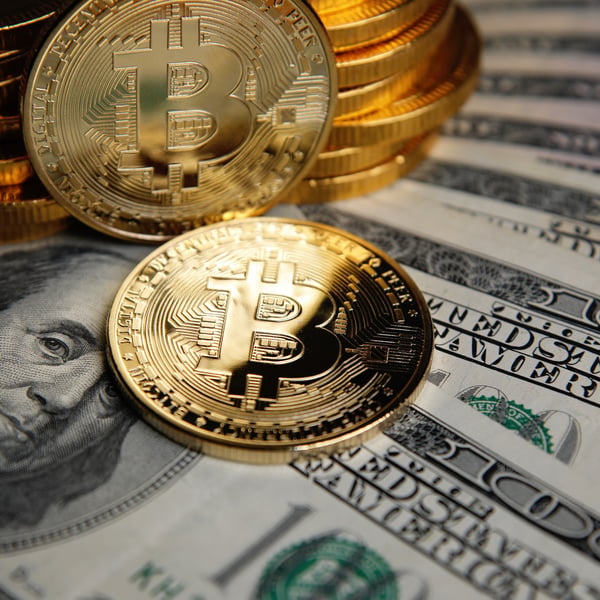 Bitcoin coins stacked on US dollar banknotes representing $130 million stolen from Coldcard hardware wallet users through a seed phrase vulnerability