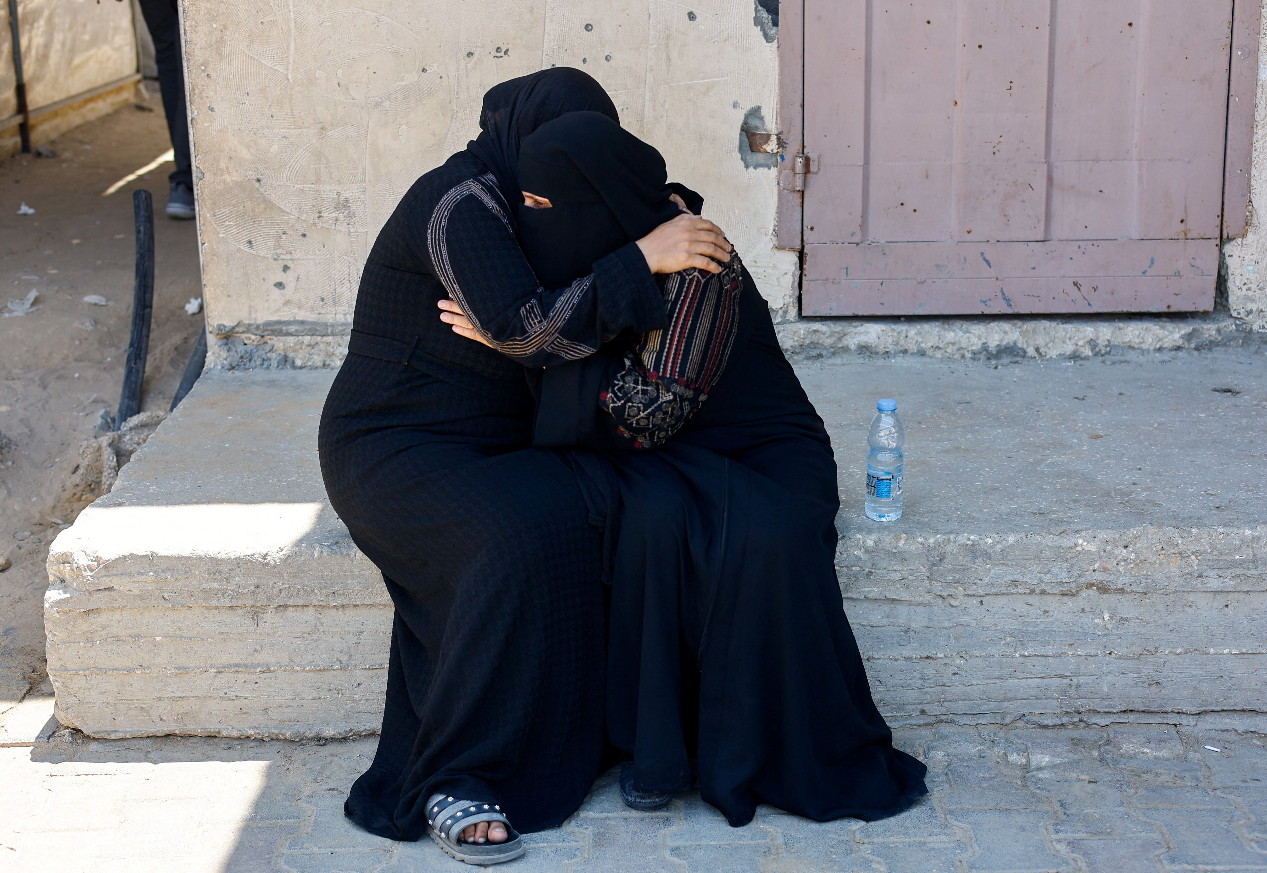 Mourners comfort each other at the funeral of Palestinian Saber Rabie, killed in an Israeli strike, at Al-Aqsa Martyrs Hospital in Deir al-Balah, central Gaza