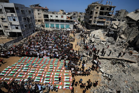 Palestinians carry coffins of 112 members of the Hassayna and Abu Sharia clans killed in an Israeli airstrike in Sabra Gaza City in 2023 during a mass funeral on August 4 2026