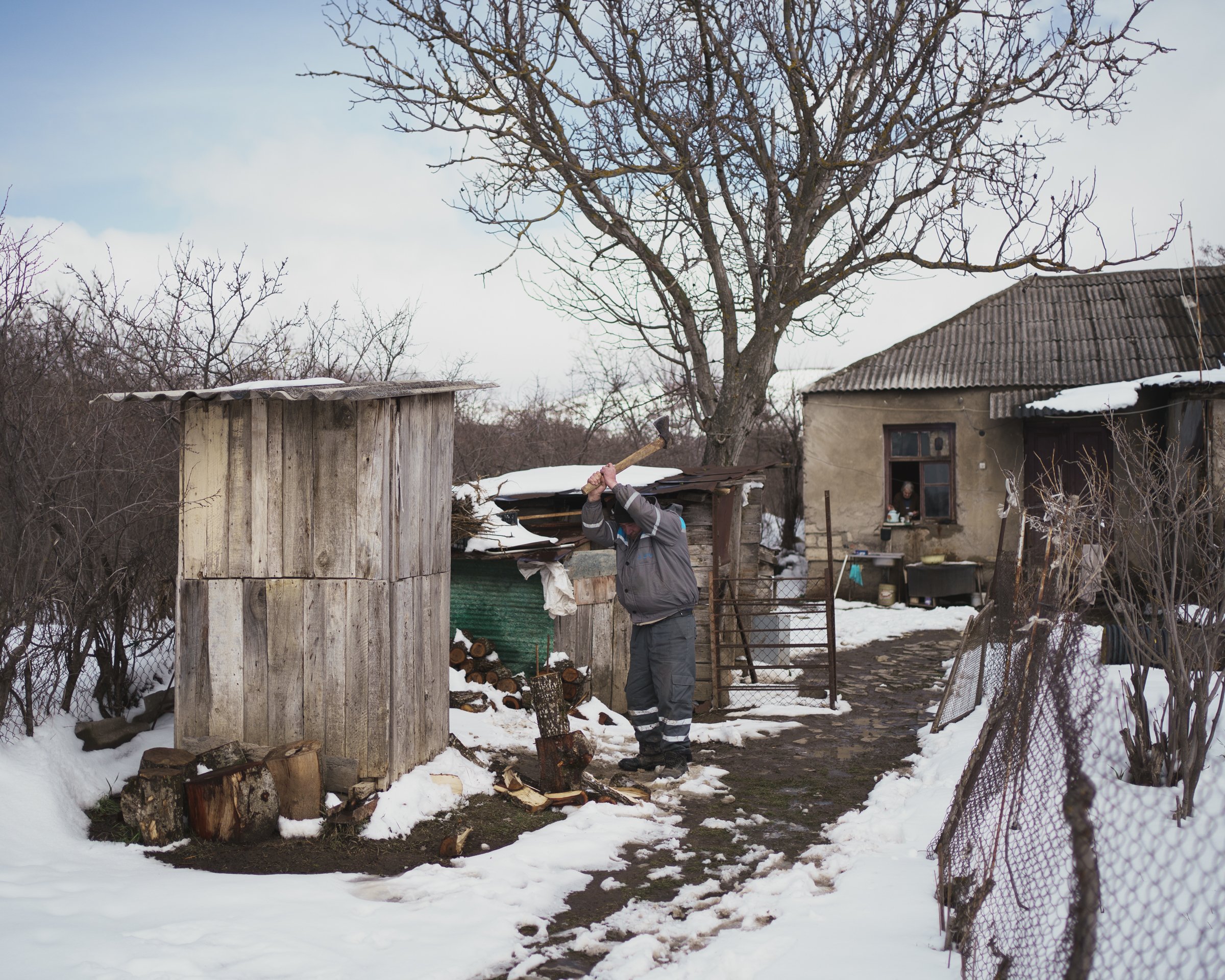 A man chops wood beside a fence in Khurvaleti, a Georgian village divided by Russian borderisation along the South Ossetia boundary line