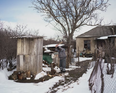 A man chops wood beside a fence in Khurvaleti, a Georgian village divided by Russian borderisation along the South Ossetia boundary line