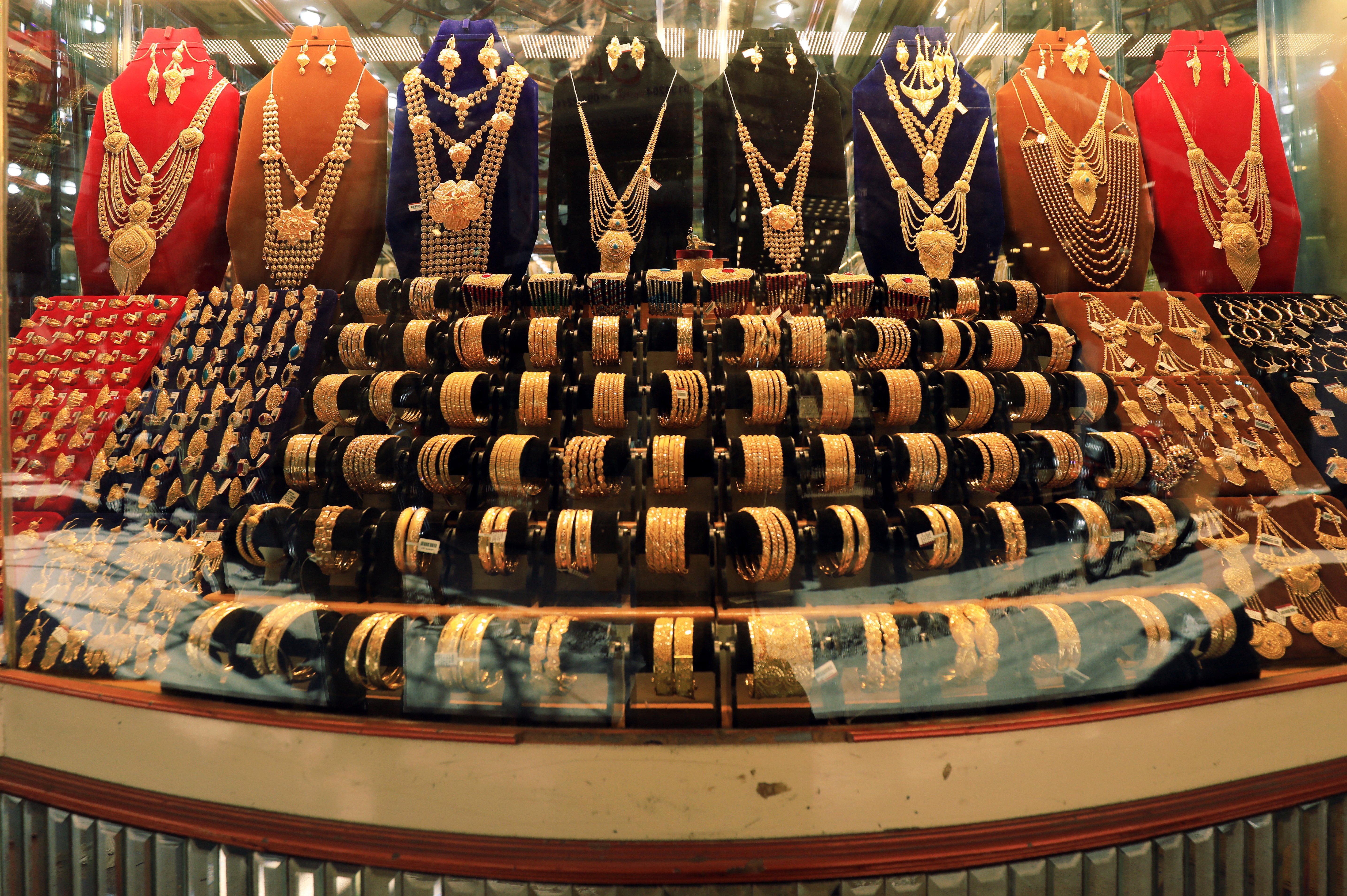 Sets of gold bangles and necklaces displayed in a bridal jewellery showroom, the heavy sets buyers are abandoning at the gold price today