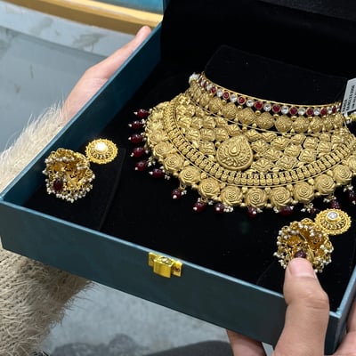 A customer examines a gold necklace at a jewellery showroom as the gold rate today holds 24K at Rs 15,928 a gram