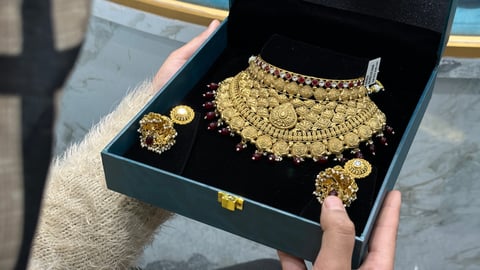 A customer examines a gold necklace at a jewellery showroom as the gold rate today holds 24K at Rs 15,928 a gram