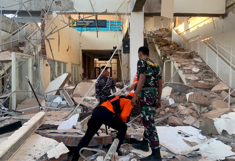 Rescue workers search through earthquake rubble on Flores Island Indonesia after 7.7 magnitude quake