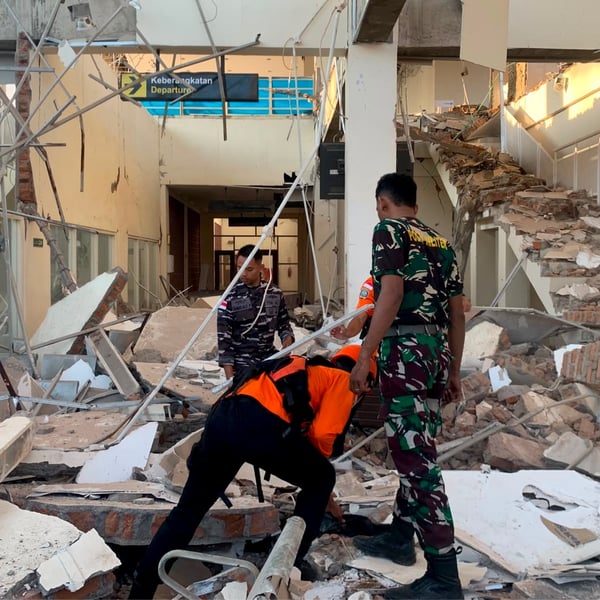 Rescue workers search through earthquake rubble on Flores Island Indonesia after 7.7 magnitude quake